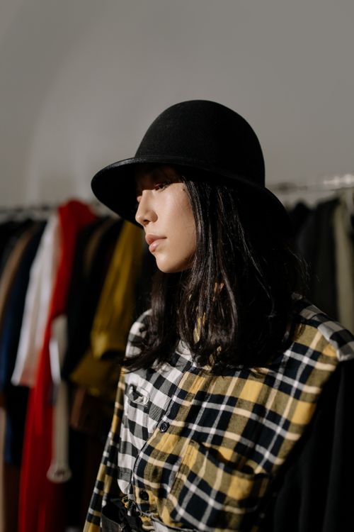 Free Stylish Asian woman wearing a black hat in a clothing shop, showcasing modern fashion. Stock Photo