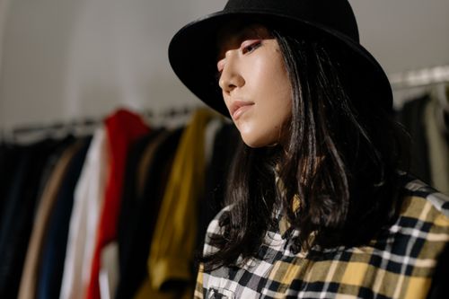 Free Portrait of a stylish woman wearing a black hat and checkered shirt in a fashion setting. Stock Photo