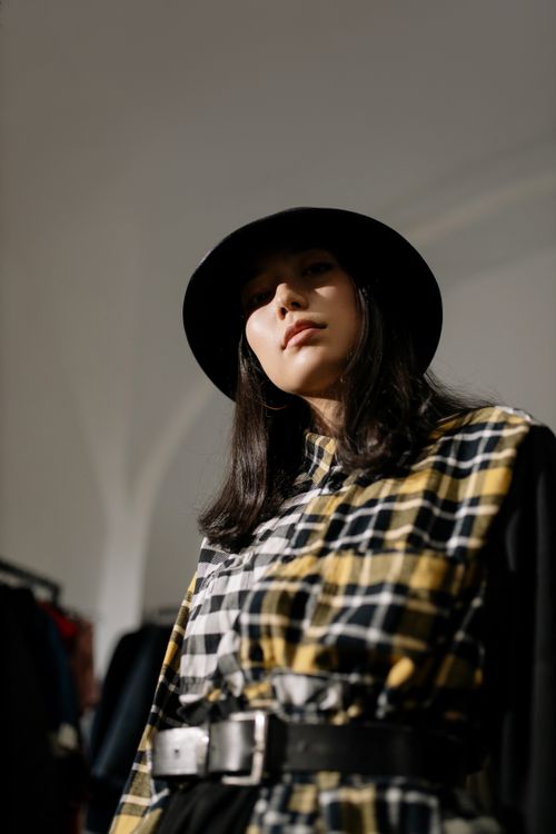 Free Woman wearing a vintage plaid outfit poses confidently indoors, exuding style. Stock Photo