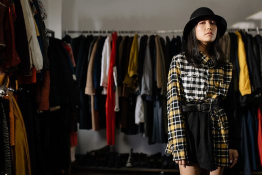 Woman in Black and White Plaid Long Sleeve Shirt Standing Near Clothes Rack