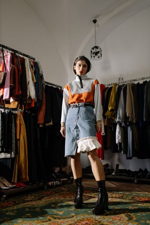 Free Fashionable woman posing in a chic clothing store amid hanging garments and racks. Stock Photo