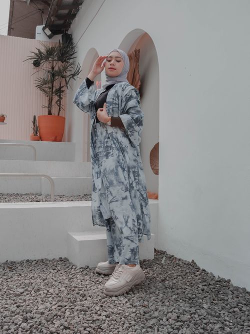 Free Side view full length beautiful ethnic female wearing stylish maxi outfit and hijab touching face and looking at camera while standing on backyard Stock Photo