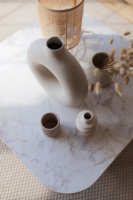 Sophisticated arrangement of ceramic vases with natural decor on a marble surface.