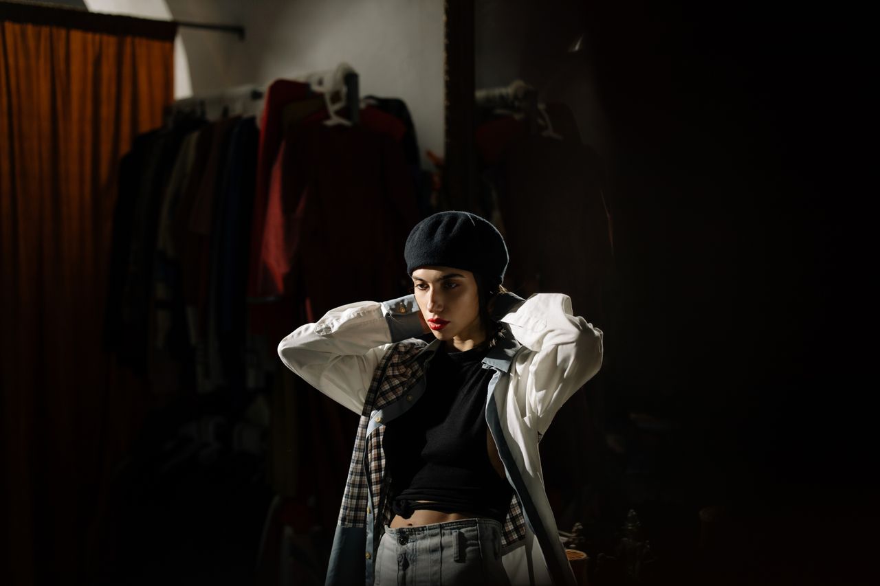 fashionable woman wearing a beret poses in a clothing store with drama