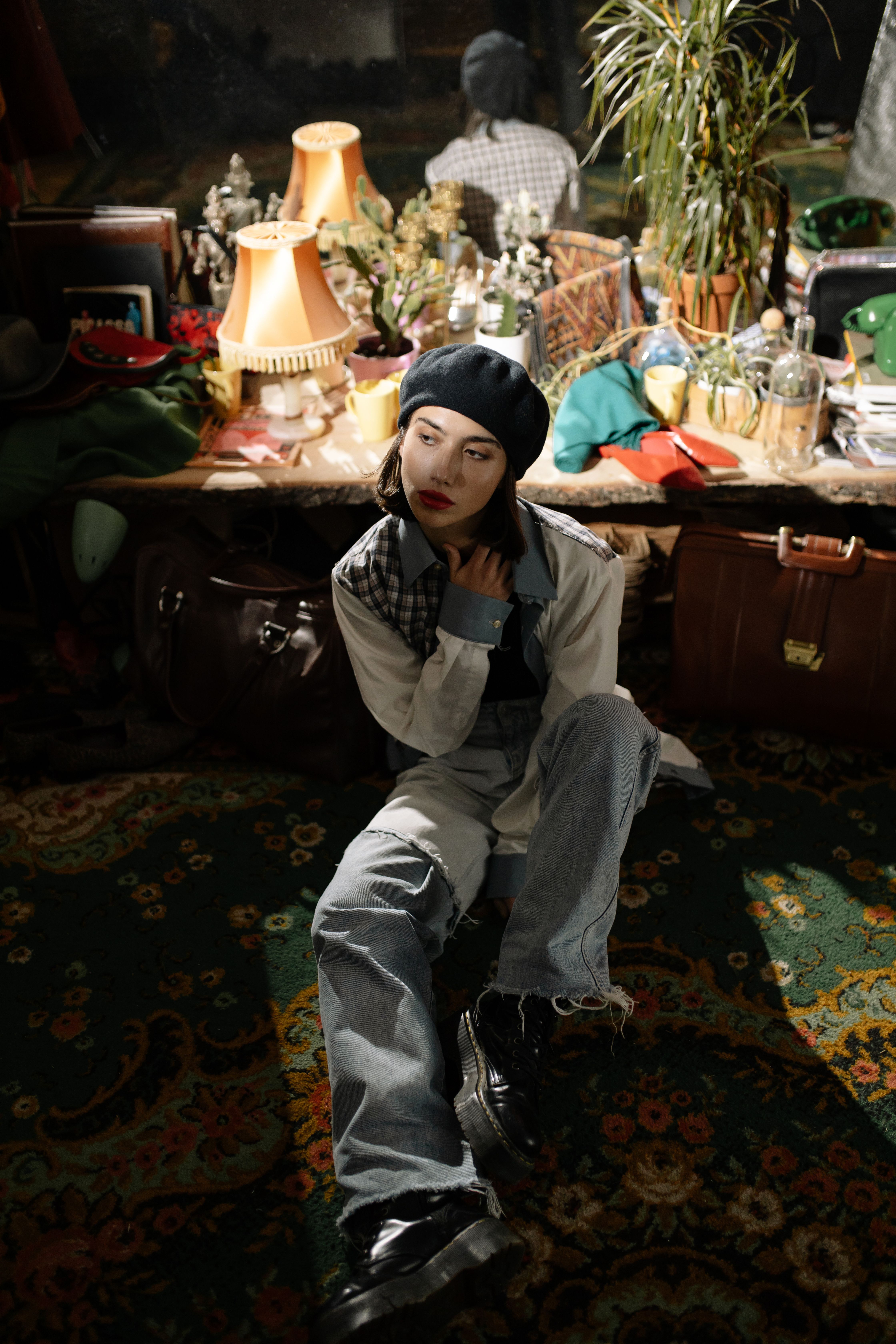 Stylish woman in beret and denim poses indoors against a vintage backdrop, exuding elegance.