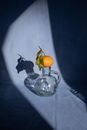 Composition of sweet ripe mandarin placed on transparent decanter on blue surface in bright sunlight