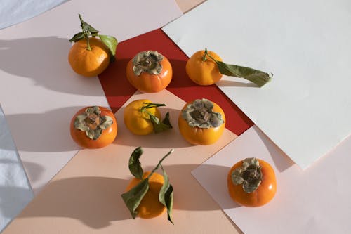 Persimmons and tangerines placed on sheets on table