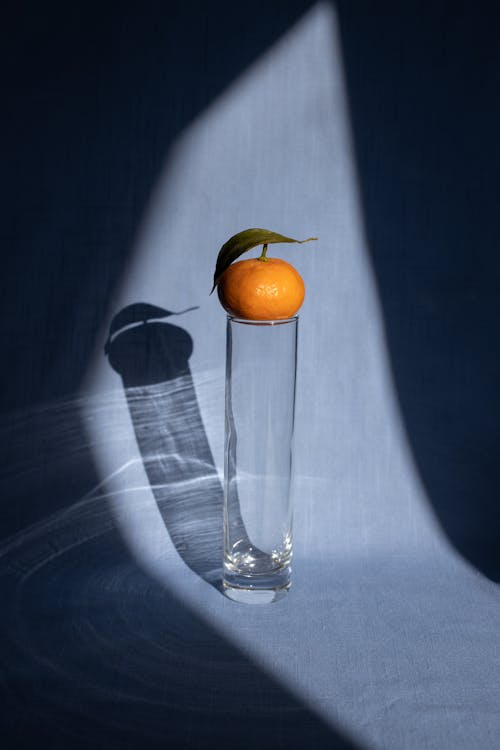 Mandarin placed on vase on blue surface