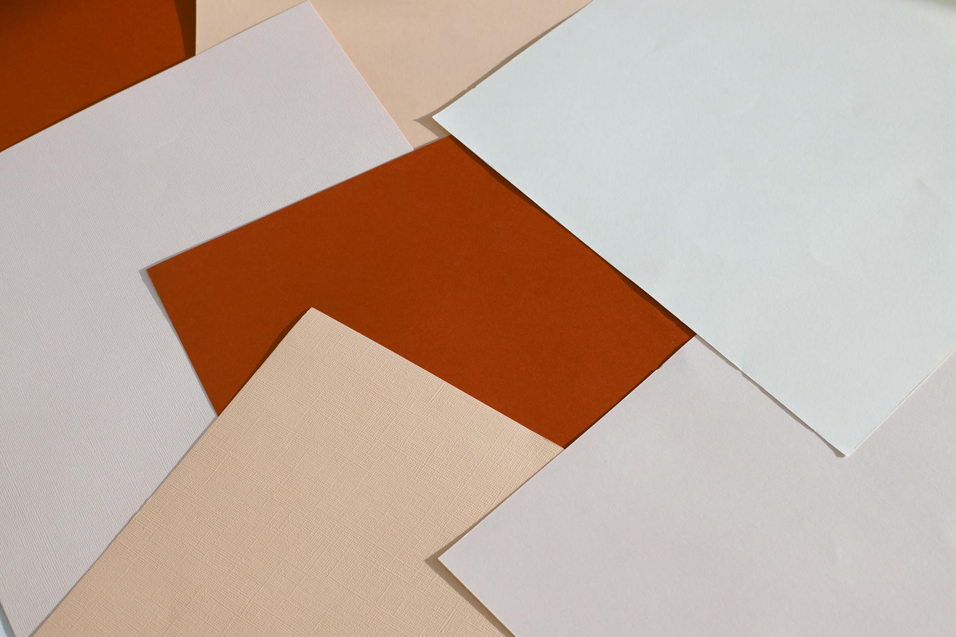 From above of blank paper sheets of different colors scattered on table as abstract background