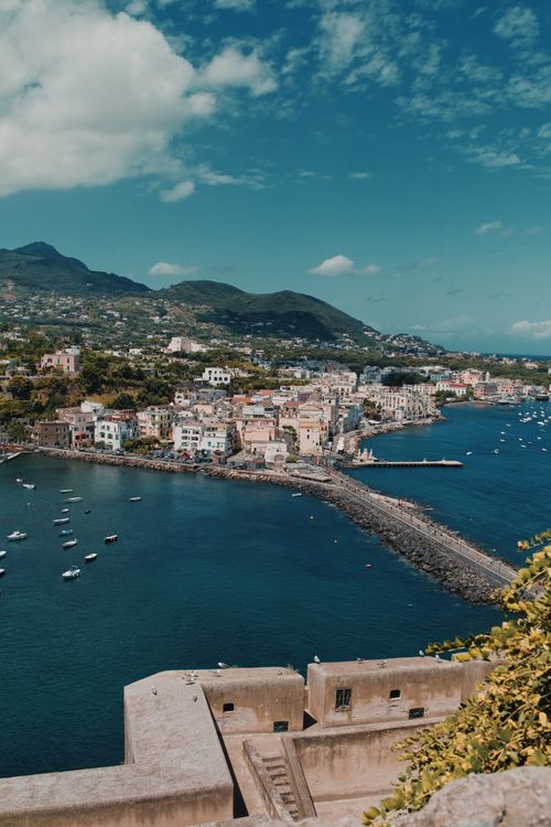Free A breathtaking aerial shot of Ischia Porto, Italy, showcasing the harbor and hills under a clear blue sky. Stock Photo