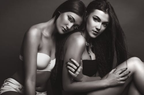 Artistic black and white photo of two women posing in lingerie during a photoshoot.