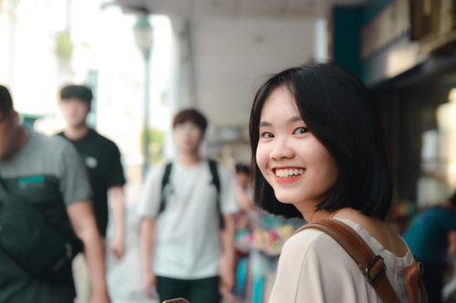 Free Young woman with black hair smiling on a vibrant city street, capturing a cheerful moment. Stock Photo