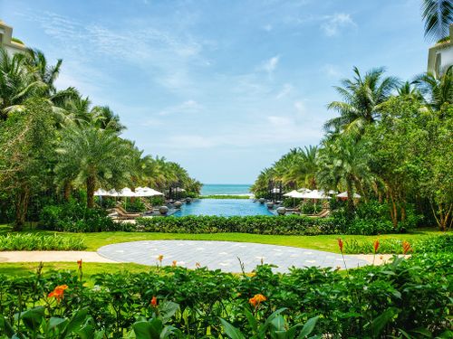 Free A lush tropical resort with an infinity pool leading to the ocean under a clear sky. Stock Photo