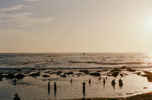 Free Silhouettes of people enjoying a tranquil beach sunset, waves gently lapping the shore. Stock Photo