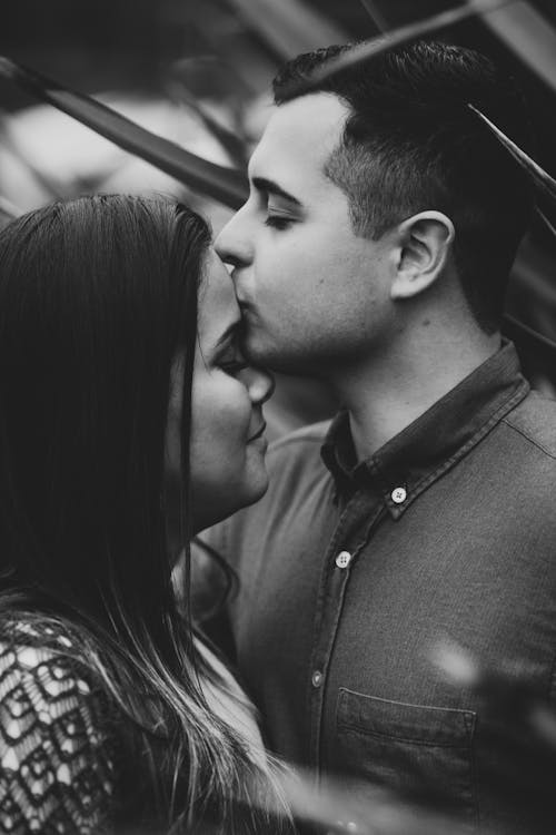 Dreamy man kissing crop smiling girlfriend on street