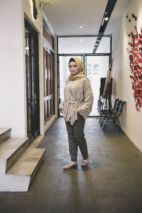 Free Woman in a hijab stands confidently indoors with sleek modern decor. Stock Photo