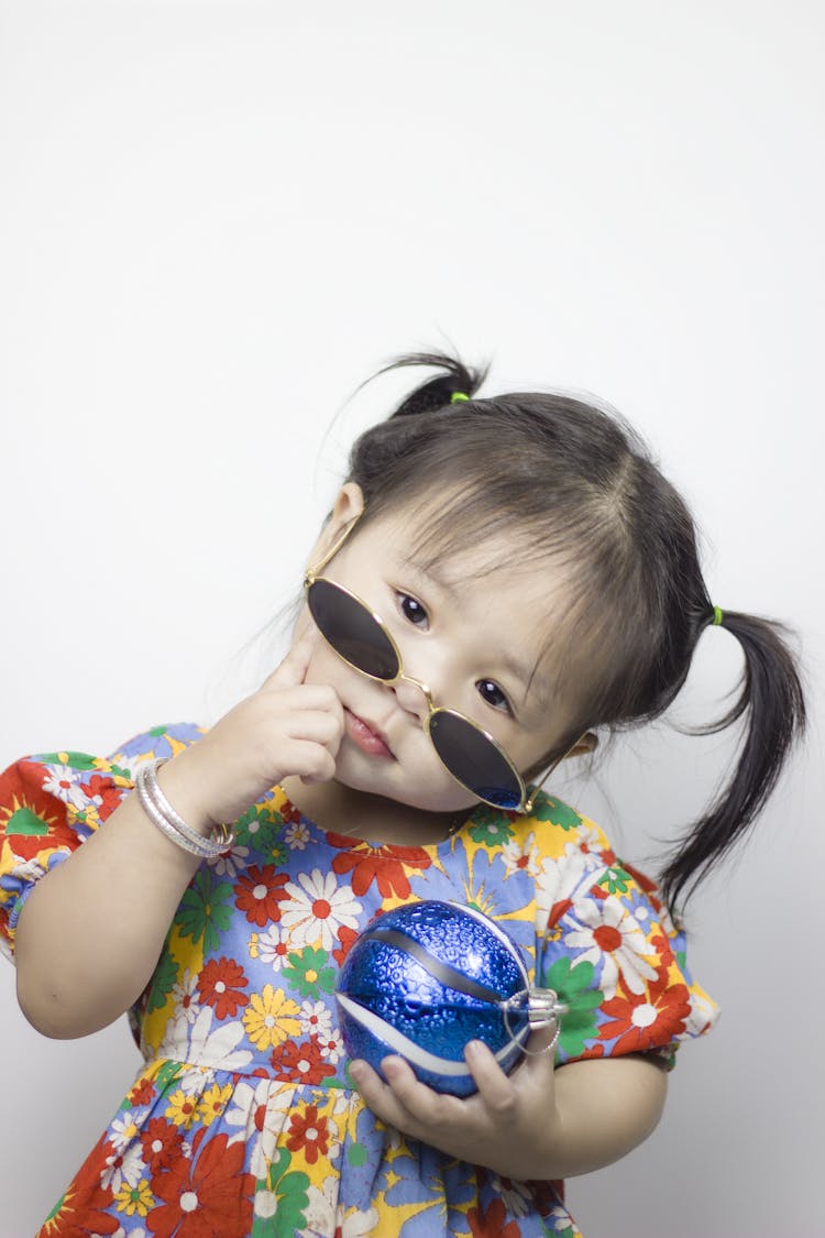 Cute Little Girl In Sunglasses Holding A Christmas Bauble 