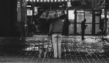 Grayscale Photo of Man in Black Jacket and Pants Holding Umbrella