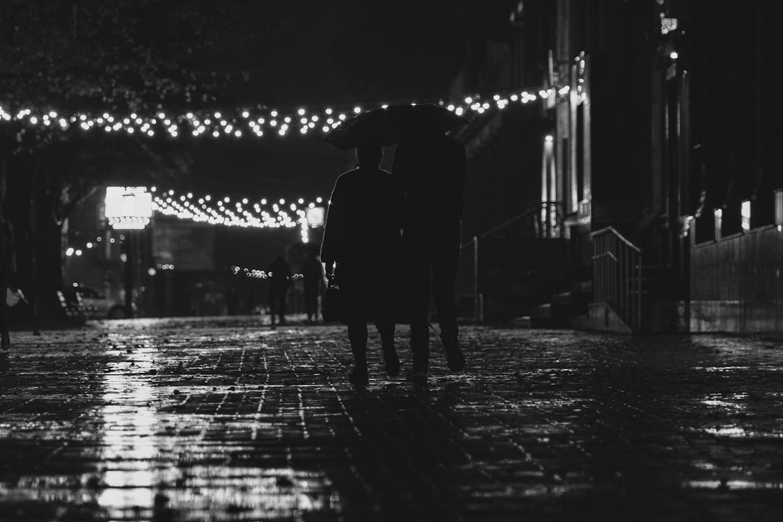Grayscale Photo of Two People Walking on the Street