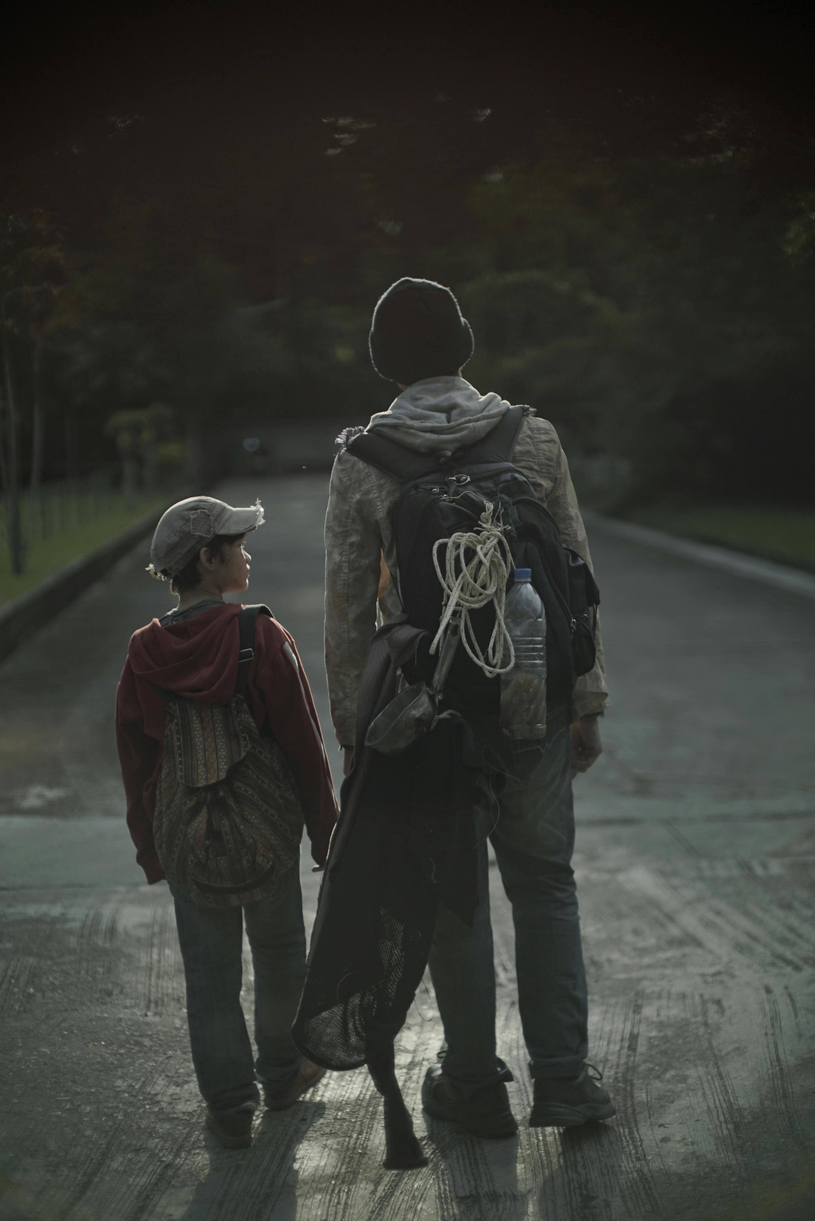 unrecognizable hoboes with backpacks walking on urban road