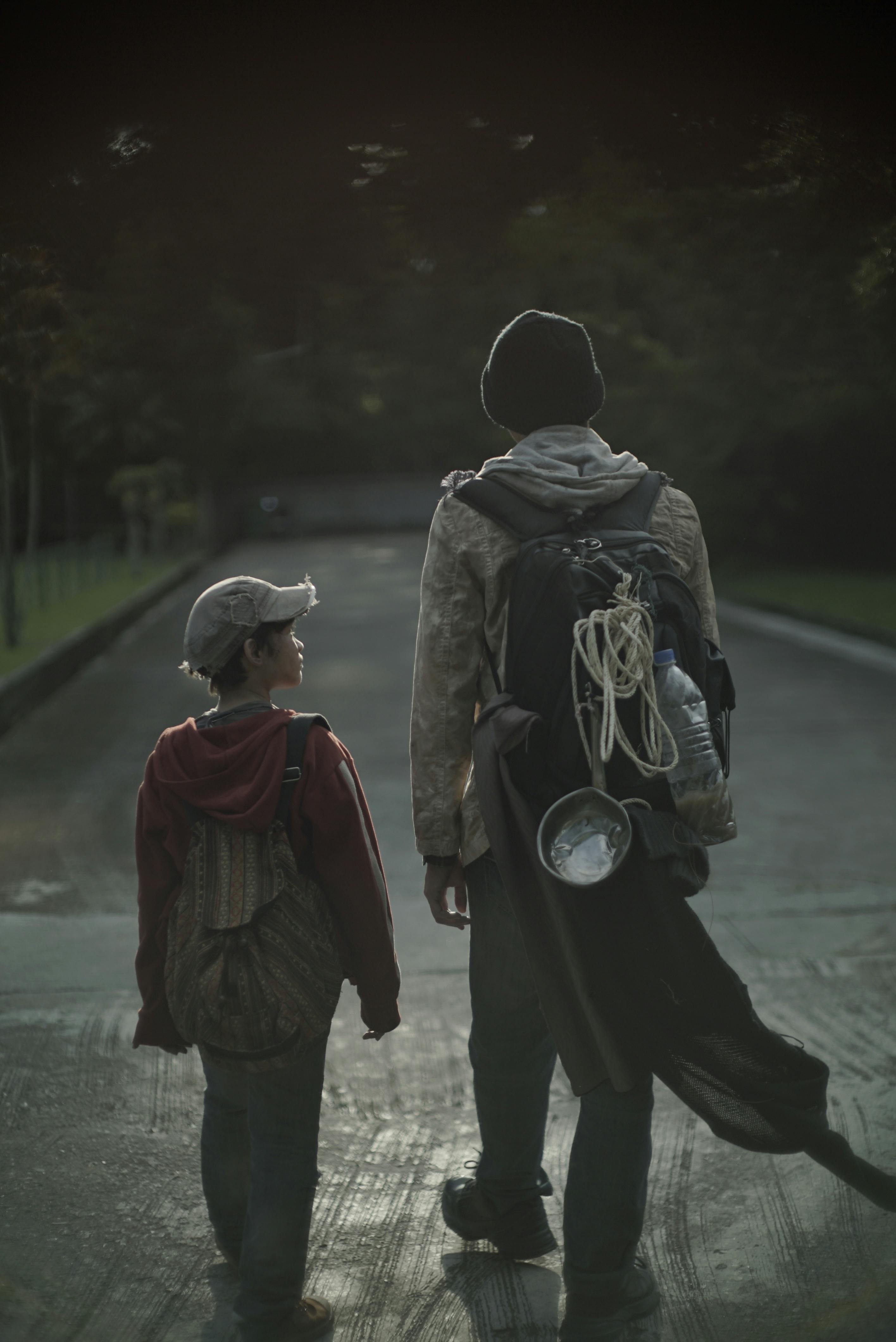 anonymous tramps with rucksacks strolling on roadway in town