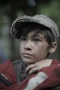 Dreamy ethnic child in casual outfit and cap looking forward on street on blurred background