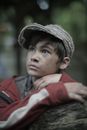 Poor wistful ethnic boy in cap in park