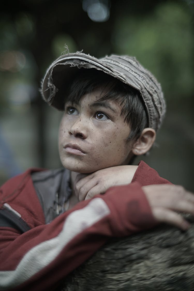 Poor Wistful Ethnic Boy In Cap In Park