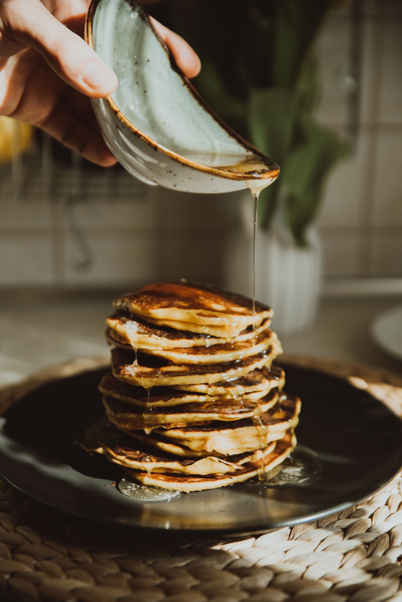 Stack of pancakes being drizzled with syrup at serving time