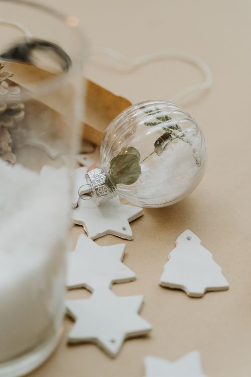 Free Delicate glass bauble with foliage inside, surrounded by ceramic ornaments, perfect for festive decor. Stock Photo