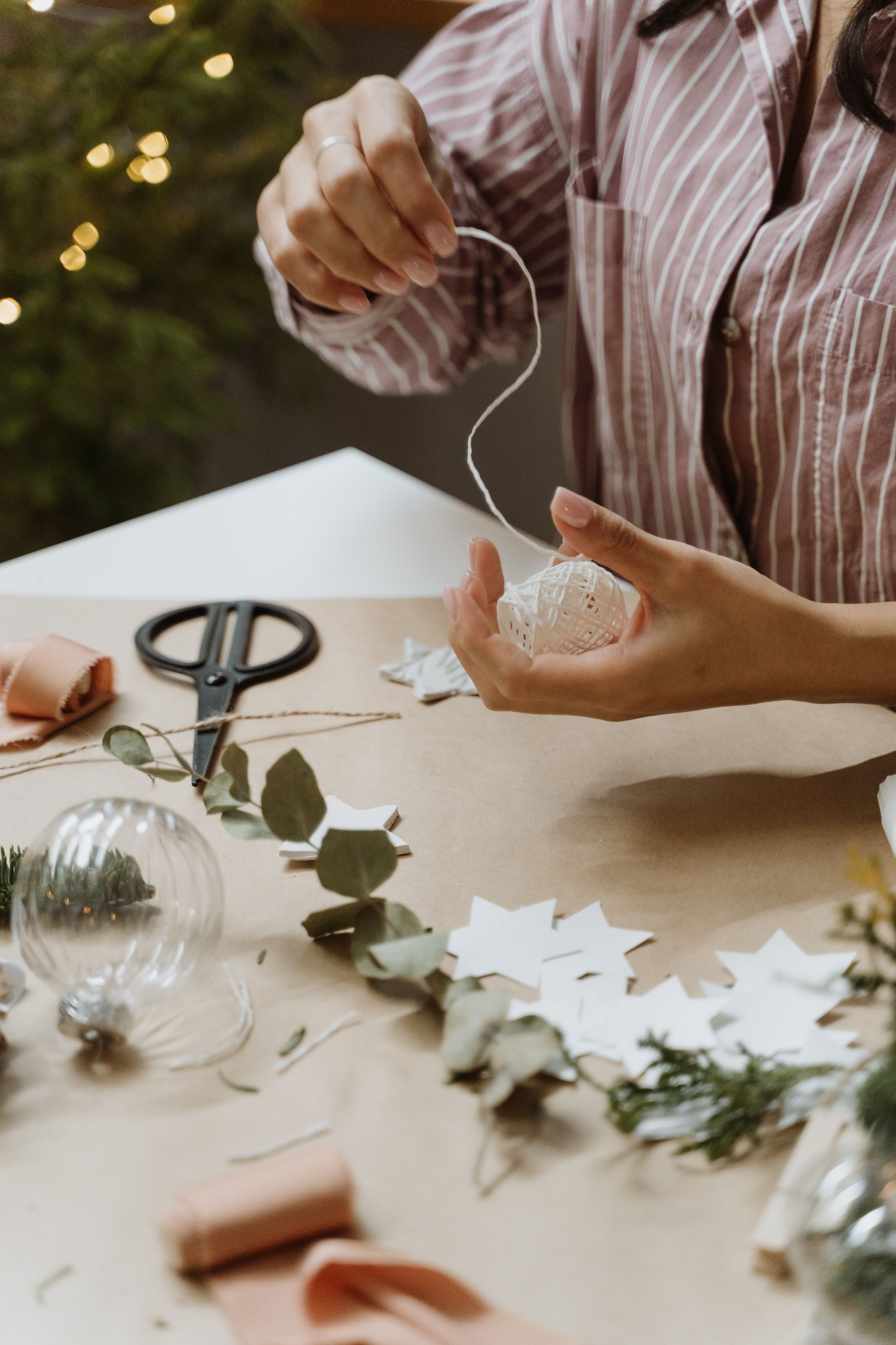 Handcrafting Christmas ornaments with paper stars and greenery.