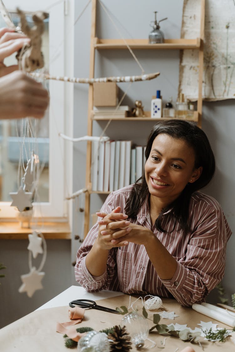 Smiling Woman Looking At Christmas Decorations In Hand