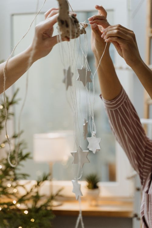 Free Two people decorating with star ornaments for Christmas indoors. Stock Photo