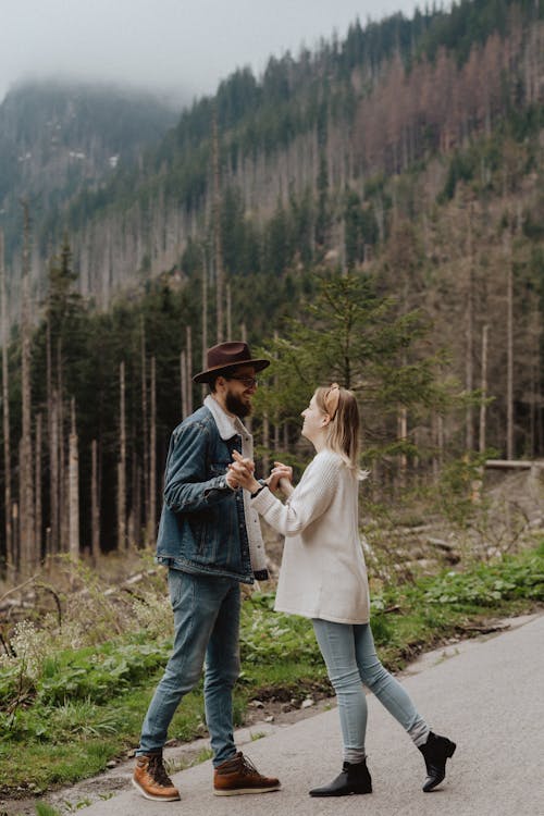 Man in Blue Denim Jacket Holding Hands Woman in White Long Sleeves 