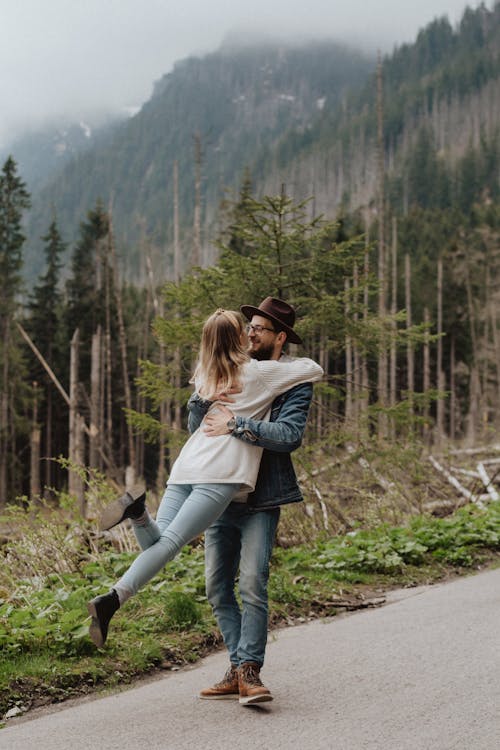 Man in Blue Denim Jacket Hugging Woman in White Long Sleeves Shirt 