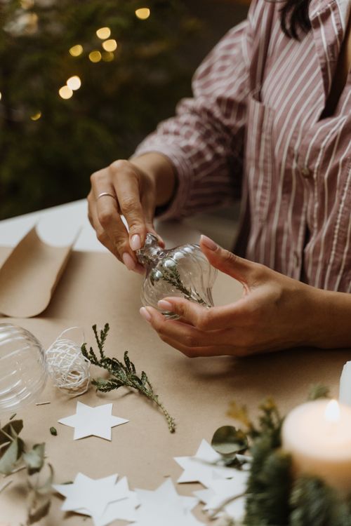Free Woman creating DIY Christmas ornaments with natural materials and candlelight. Stock Photo
