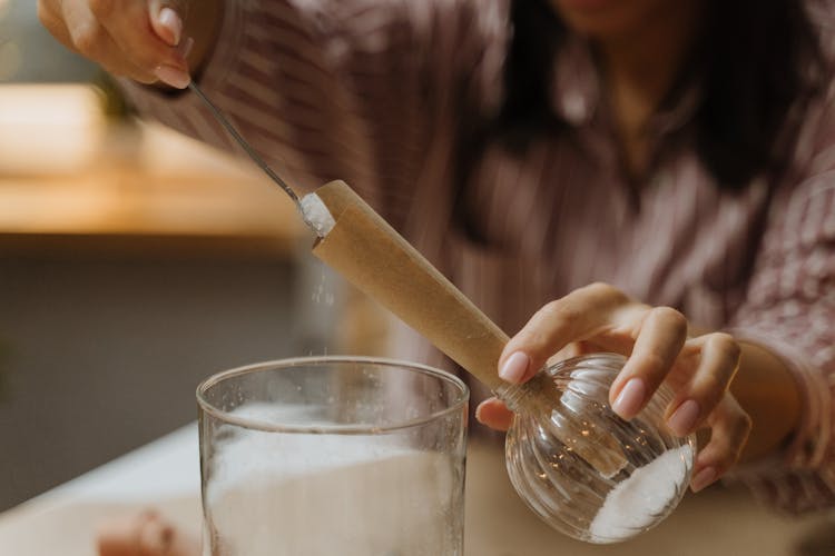 Woman Putting Sugar To A Glass Bottle With Brown Paper Funnel