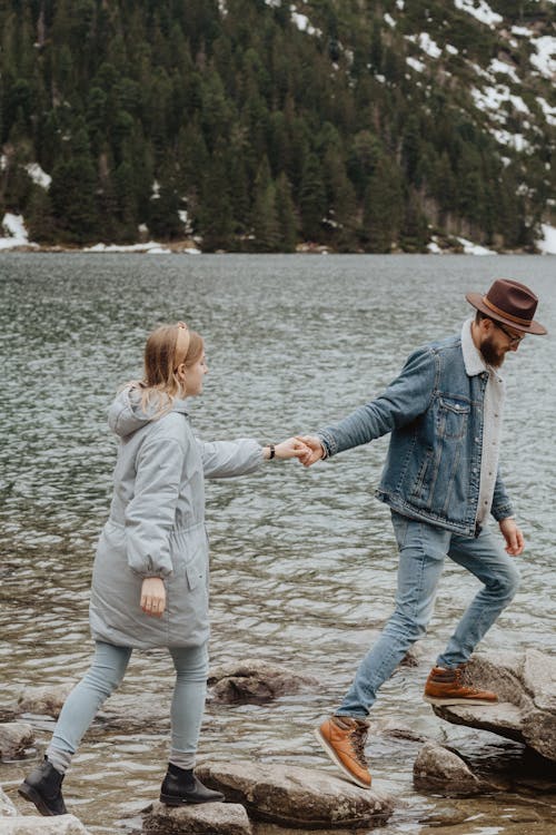 Man and Woman Stepping On Rocks To Cross A Lake · Free Stock Photo