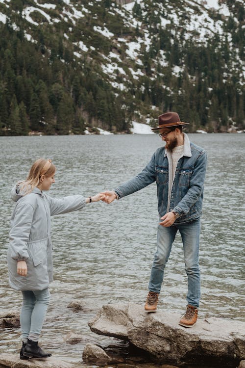 Man Helping A Woman Step On A Rock