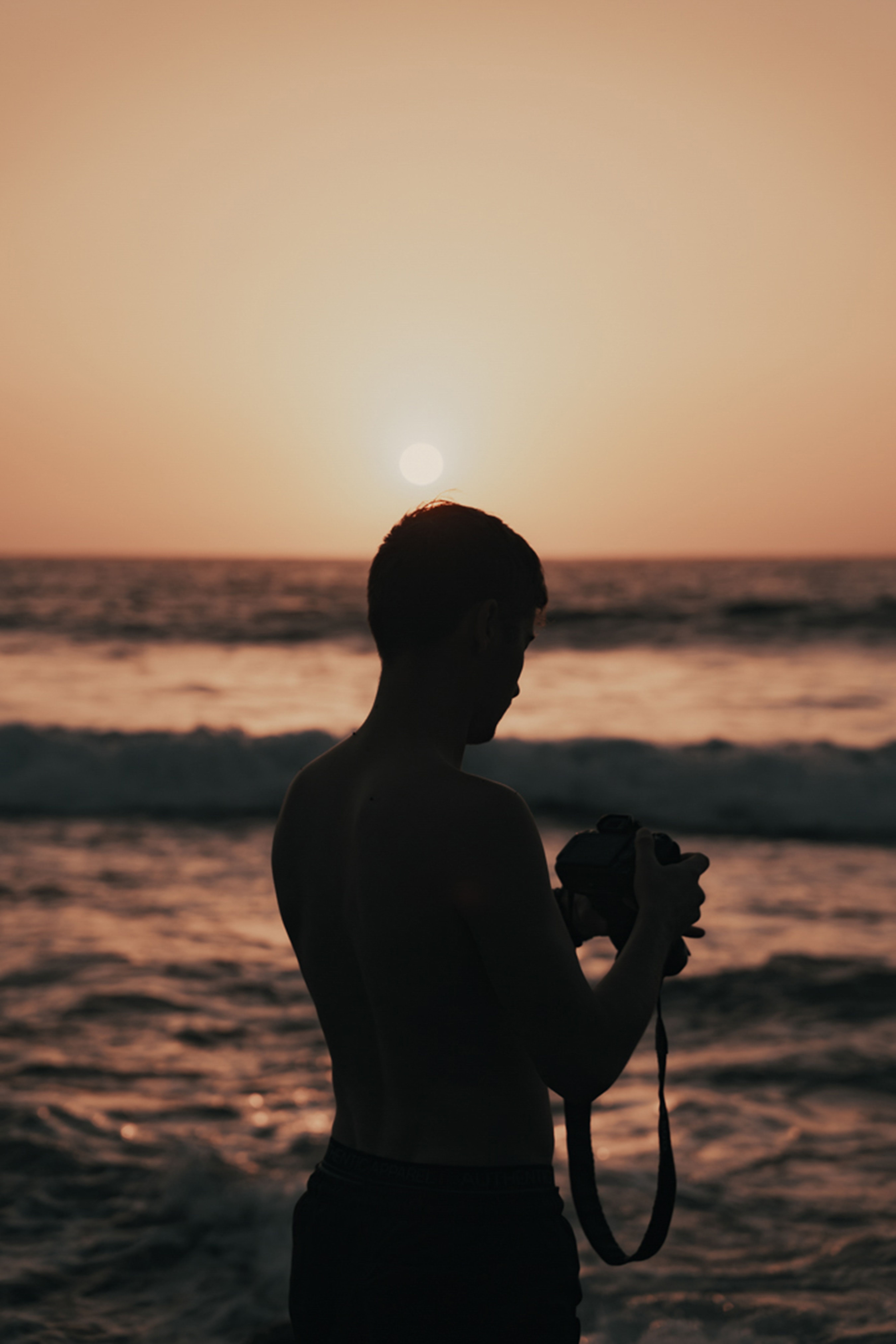 Silhouette of a man with a camera at sunset on Santa Cruz beach, Tenerife.
