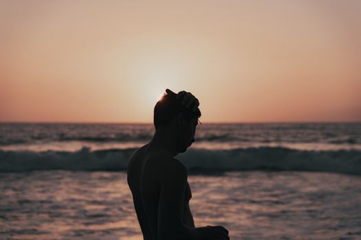 Silhouette of man touching head at sunset by the seaside in Santa Cruz de Tenerife, Spain.