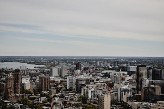 Panoramic view of Montreal cityscape featuring modern high-rise buildings and Jacques Cartier Bridge.