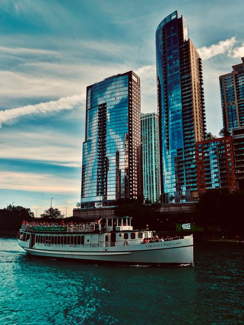 Free Boat sailing along Chicago's modern skyline during sunset, showcasing skyscrapers on the water. Stock Photo