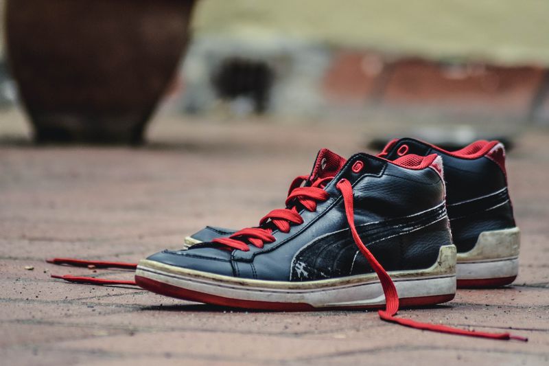 Close-up of rugged black and red sneakers on a brick pavement, showcasing urban style.