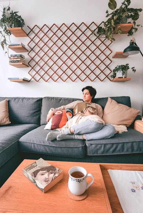 A Woman Sitting on a Couch While Holding a Book