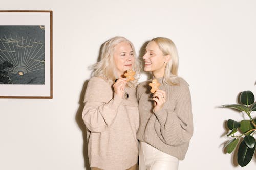 Mother And Daughter Standing Close To Each Other Holding Cookies