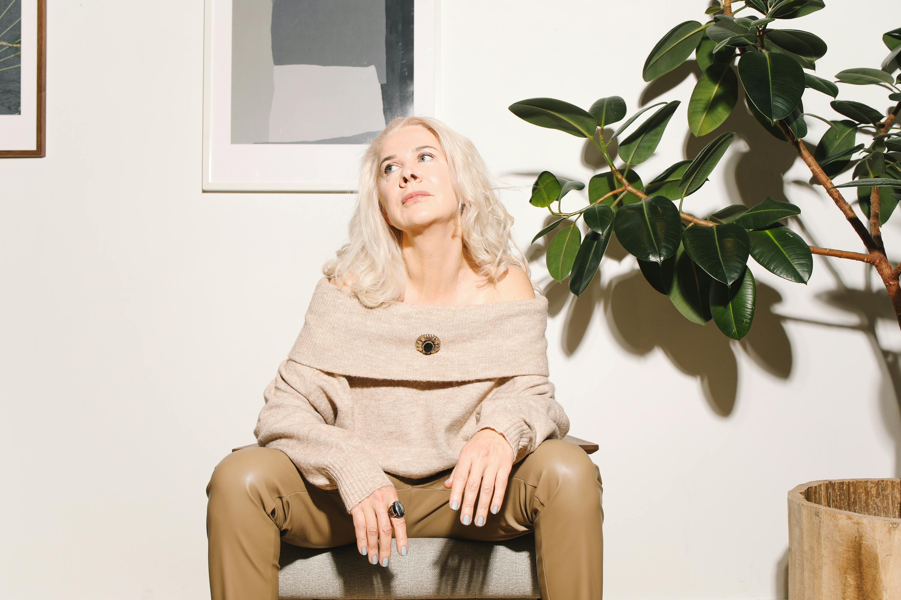 woman in beige off shoulder sweater sitting on chair