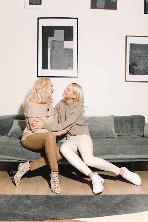 Mother And Daughter Sitting On A Gray Couch Face  To Face