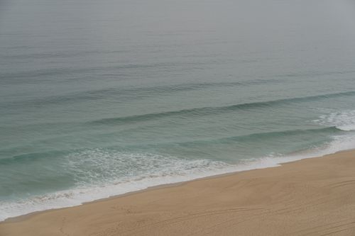 Free Peaceful beach scene with gentle waves and sandy shore in Portugal, perfect for travel and nature themes. Stock Photo