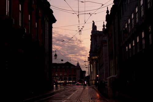 Free Urban street view of Lisbon with tram lines silhouetted against twilight sky. Stock Photo
